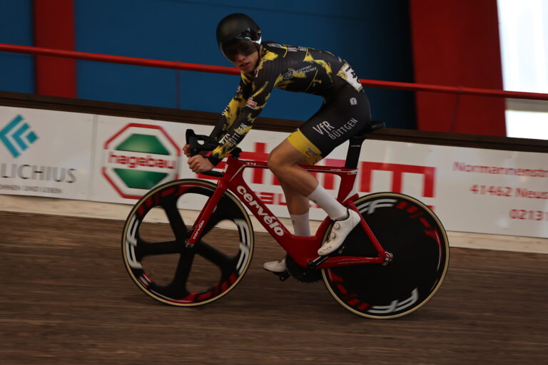 Jugendlicher Bahnradfahrer im VfR Büttgen Trikot auf rotem Bahnrad mit Scheibenrädern auf der Radrennbahn.